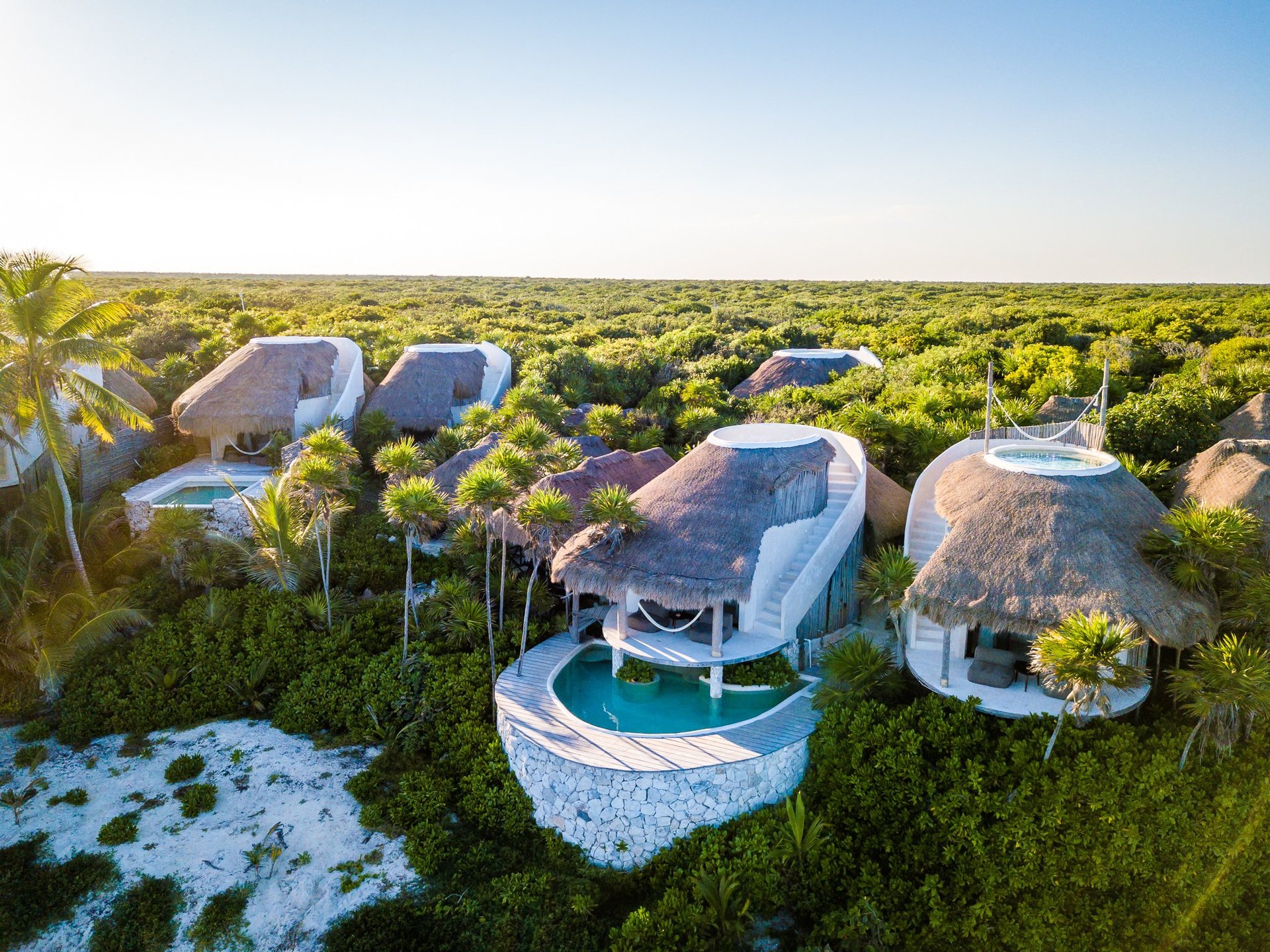 Aerial view of luxury dome-shaped accommodation structures nestled in lush green landscape with a pool feature